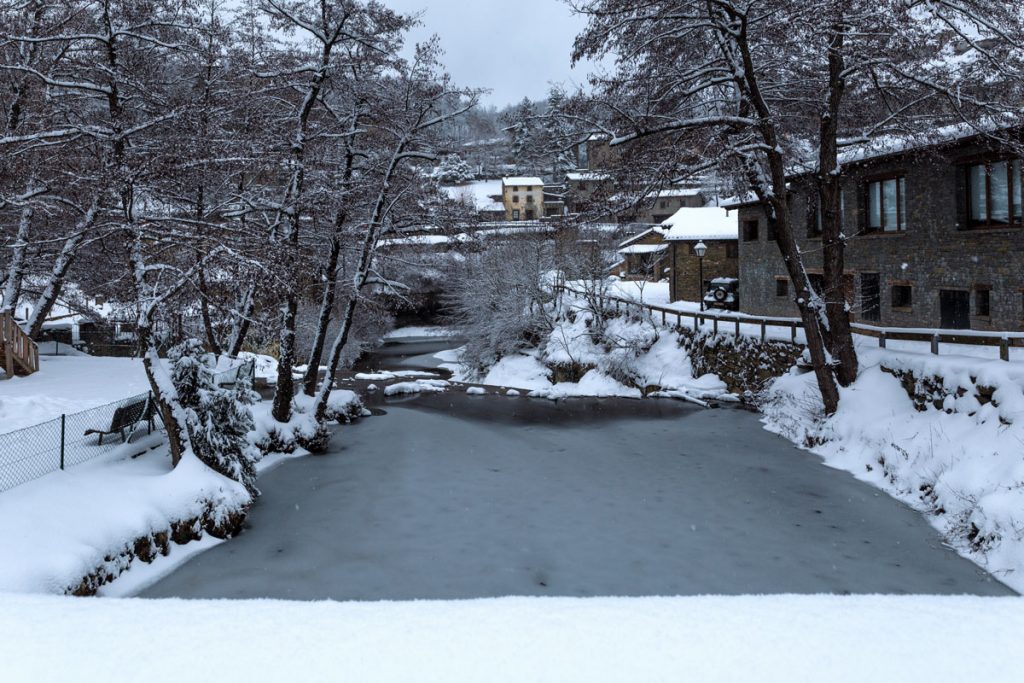 Vereister Fluss in winterlichem Dorf.