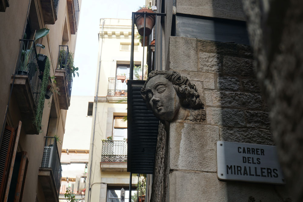 Ein an einer Häuserwand in Barcelona angebrachtes Gesicht aus Stein.