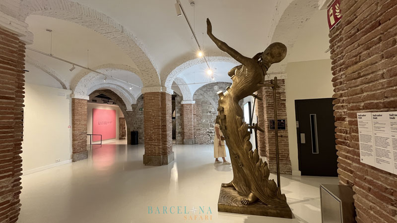 Eine goldfarbene Statue mit ausgestrecktem Arm, von Salvador Dalí.