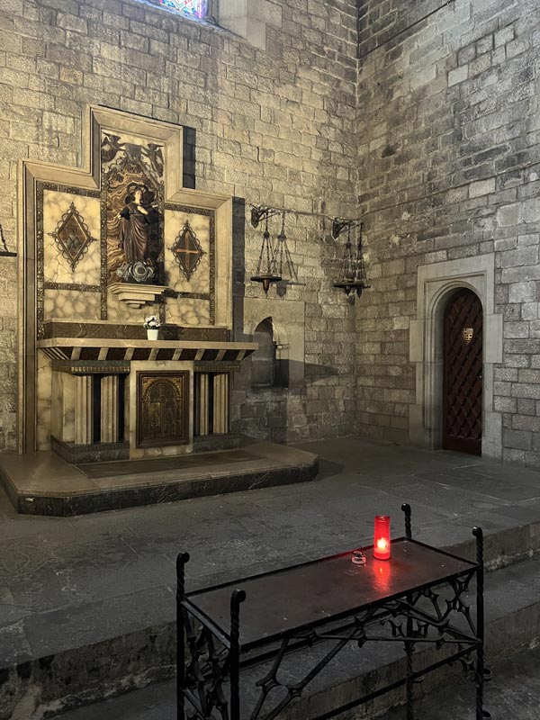 Kleine Holztüre neben einem Altar, die zum Dach der Kirche führt.