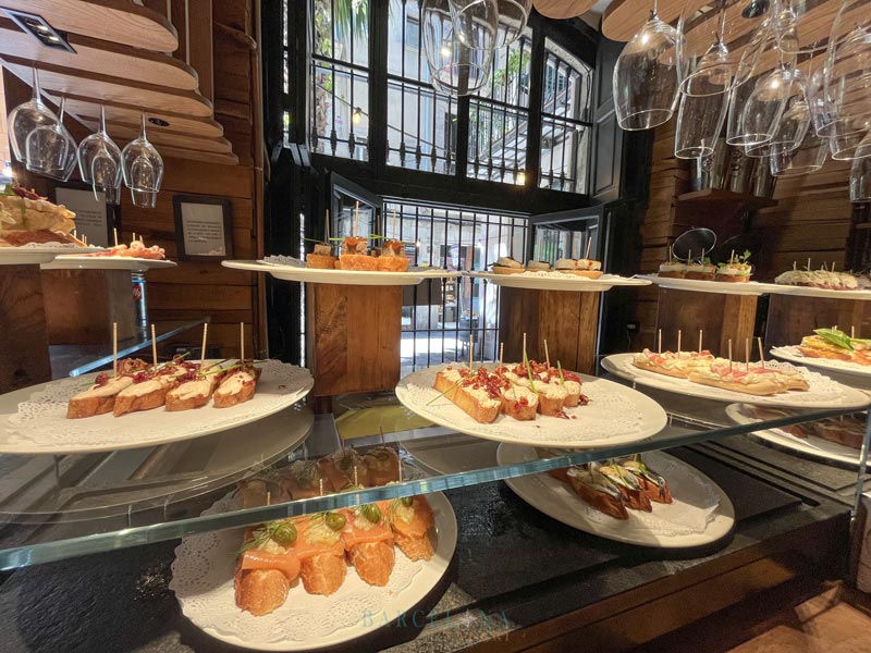 Glasvitirine einer Bar mit mehreren Tellern verschiedener Pintxos-Tapas.