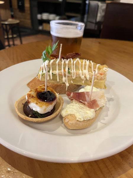 Ein Teller mit 3 Pintxos und ein Glas Bier.