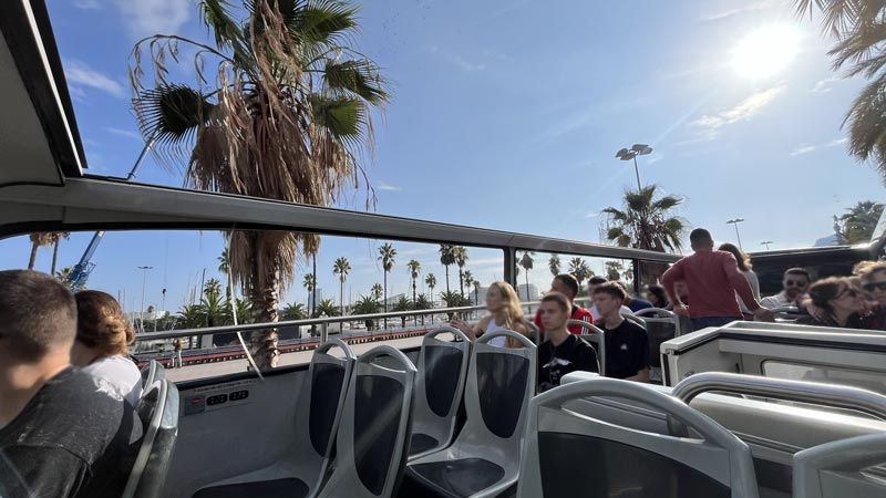 Vom Oberdeck des Bus der roten Route hat man Blick auf die Palmen und die Schiffe im Hafen.