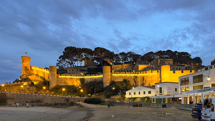 Die ummauerte Altstadt von Tossa de Mar beleuchtet in der Abenddämmerung.