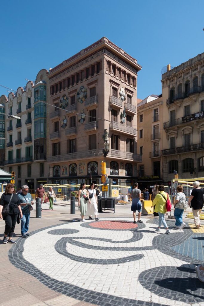 Teil des Miró Gemäldes auf dem Pflaster der Rambla, im Hintergrund ist das Haus der Schirme zu sehen, das aufgrund seiner Dekoration so gennant wird.